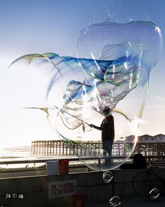 Image of a man with a giant bubble making wand on Pacific Beach California